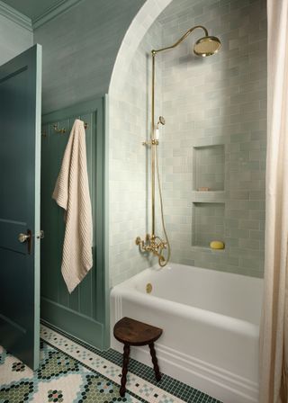 A bathroom with a classic bathtub and brass showe