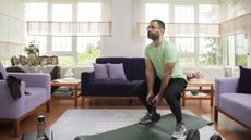 Man exercising with dumbbells at home in living room