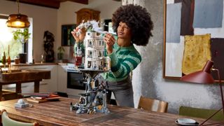 Lego Gringotts Bank being carefully assembled on a wooden table by a woman