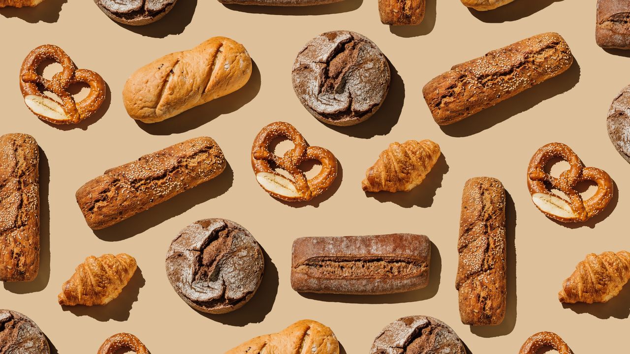 Pattern of various bakery products handmade on beige background. Creative layout with bread, buns, croissant, bread loaves and pretzels.