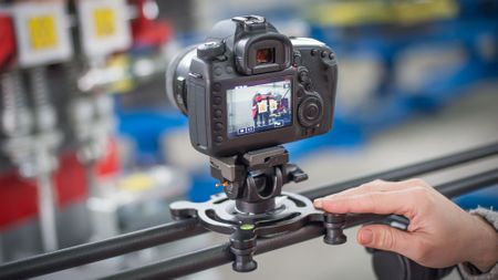 Videographer using camera slider, making video of business at factory