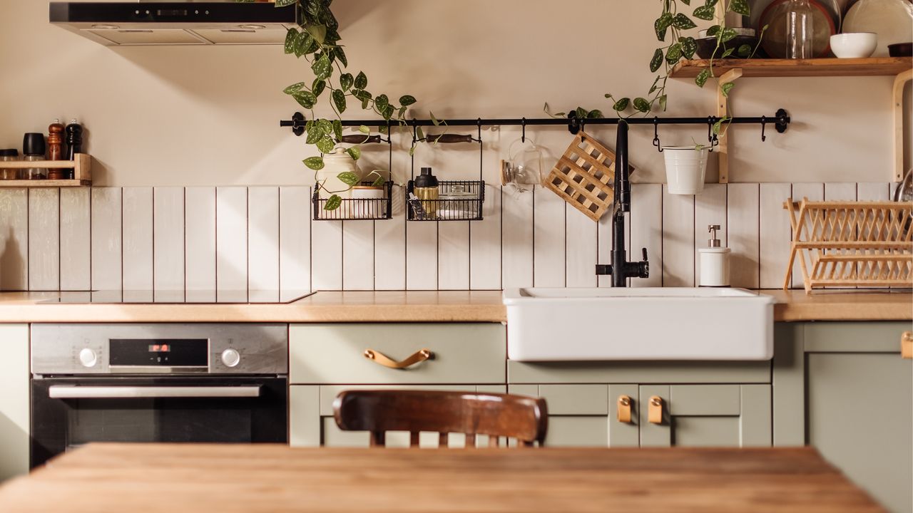 Kitchen with wooden counters light green cabinets wall shelving and white ceramic butler&#039;s sink