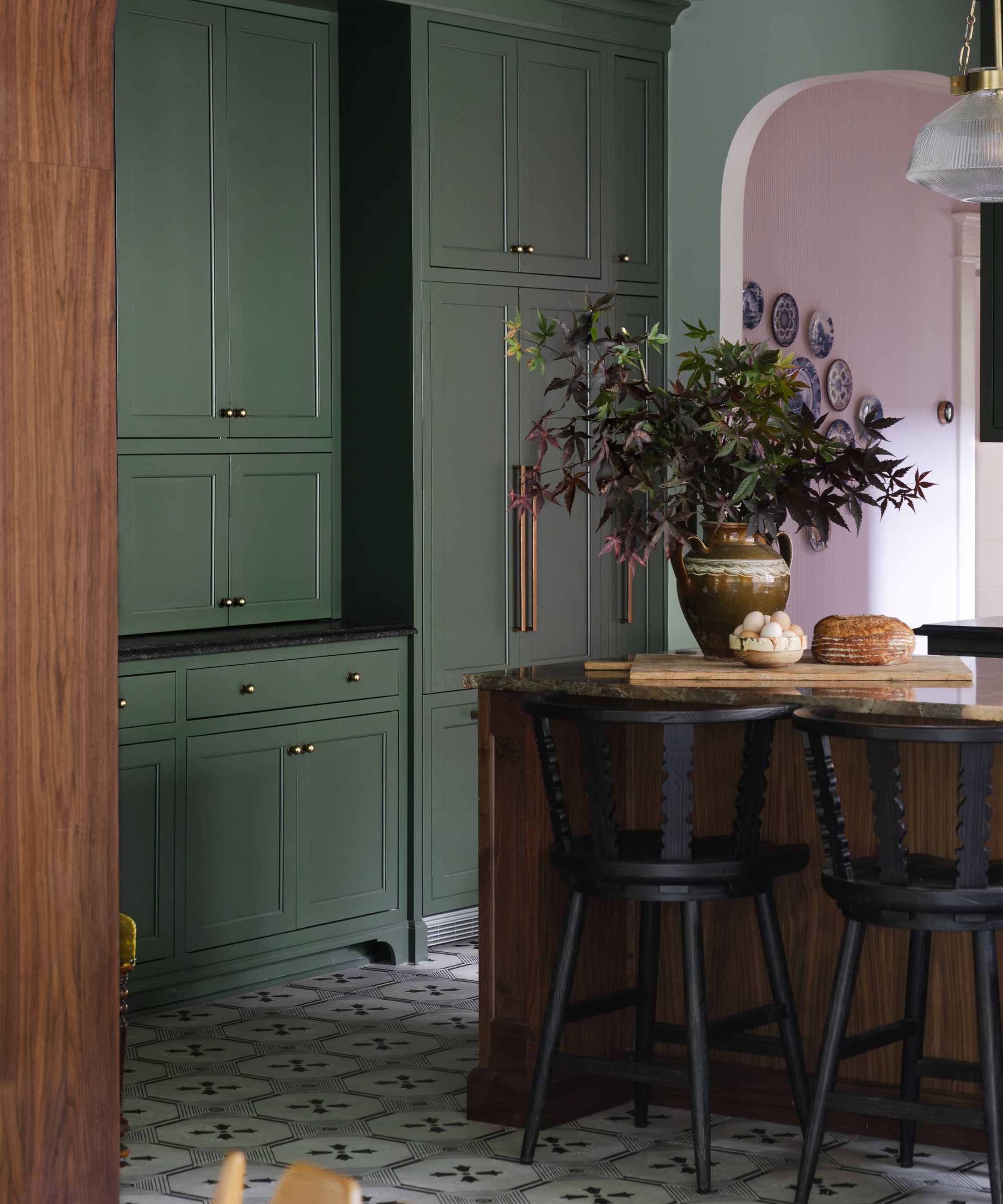 A kitchen with dark green floor to ceiling cabinets and a dark wood island