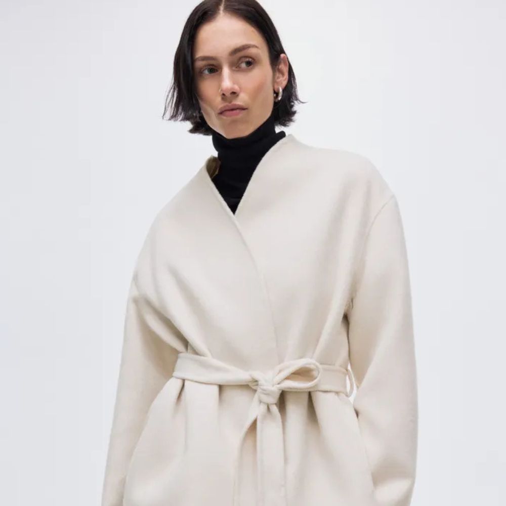 Woman wears black turtleneck and white collarless jacket