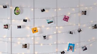 A string of lights holds up pictures on a wall.