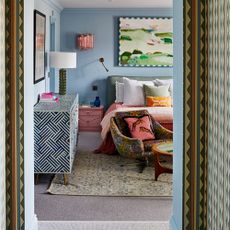 A sky blue-painted bedroom with a botanical-patterned rug on the floor