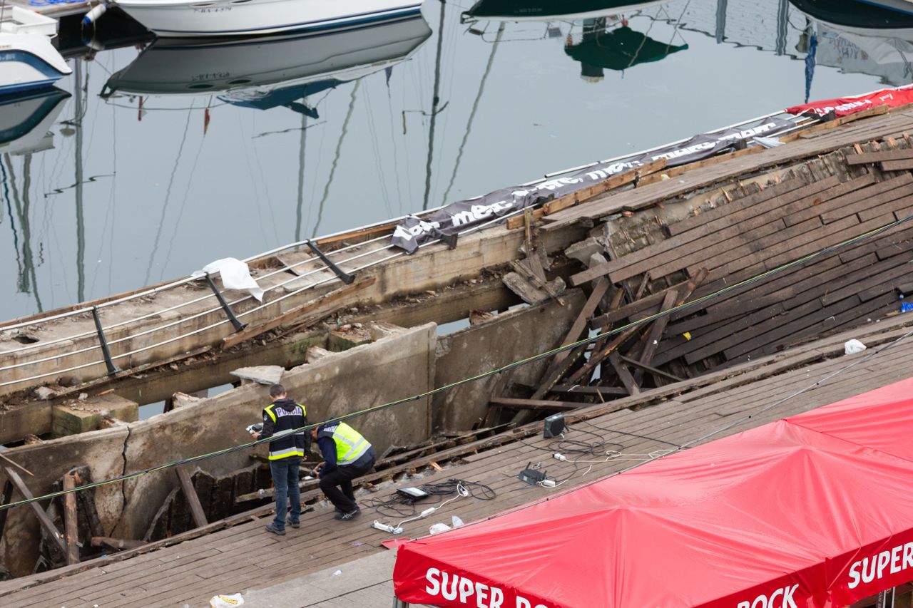 Police investigators inspect the seafront platform in Vigo on August 13, 2018 after a section of a wooden promenade suddenly collapsed with people watching a rap artist just before midnight o