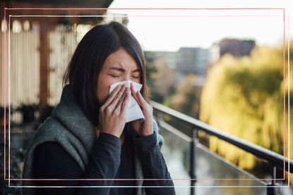 Woman in need of natural remedies for hay fever sneezing into a tissue whilst standing outside