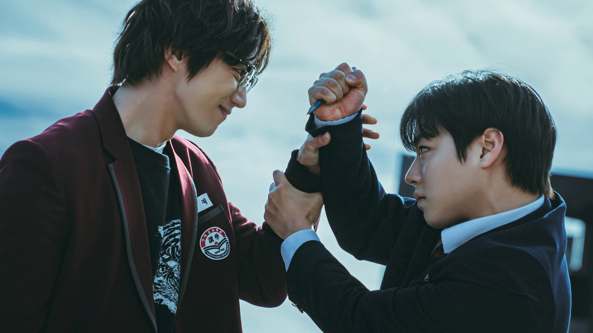 A teen in a red school blazer (Lee Jun-young as Geum Seongje) fights with another teen in a blue blazer (Park Ji-hoon as Yeon Sieun) in Weak Hero Class 2.