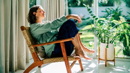 Happy woman sitting in the sun in the morning sunshine at home