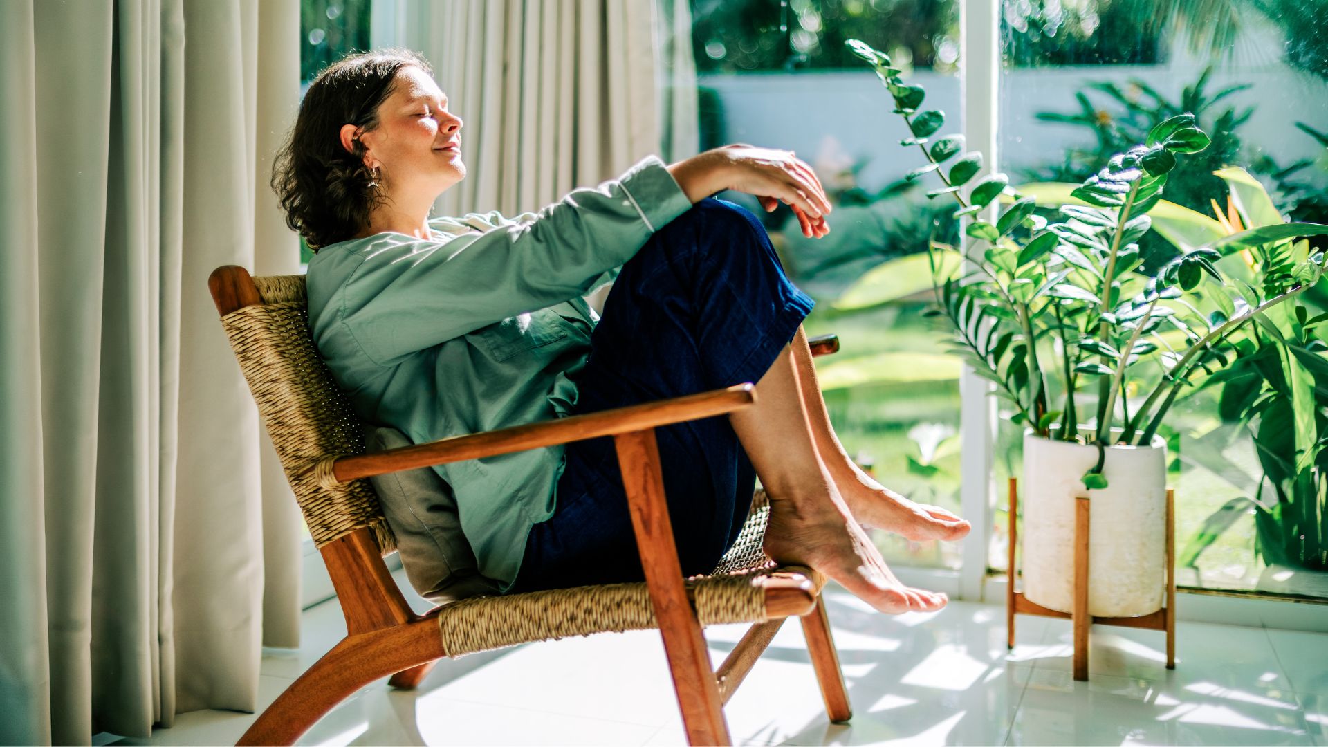 Happy woman sitting in the sun in the morning sunshine at home
