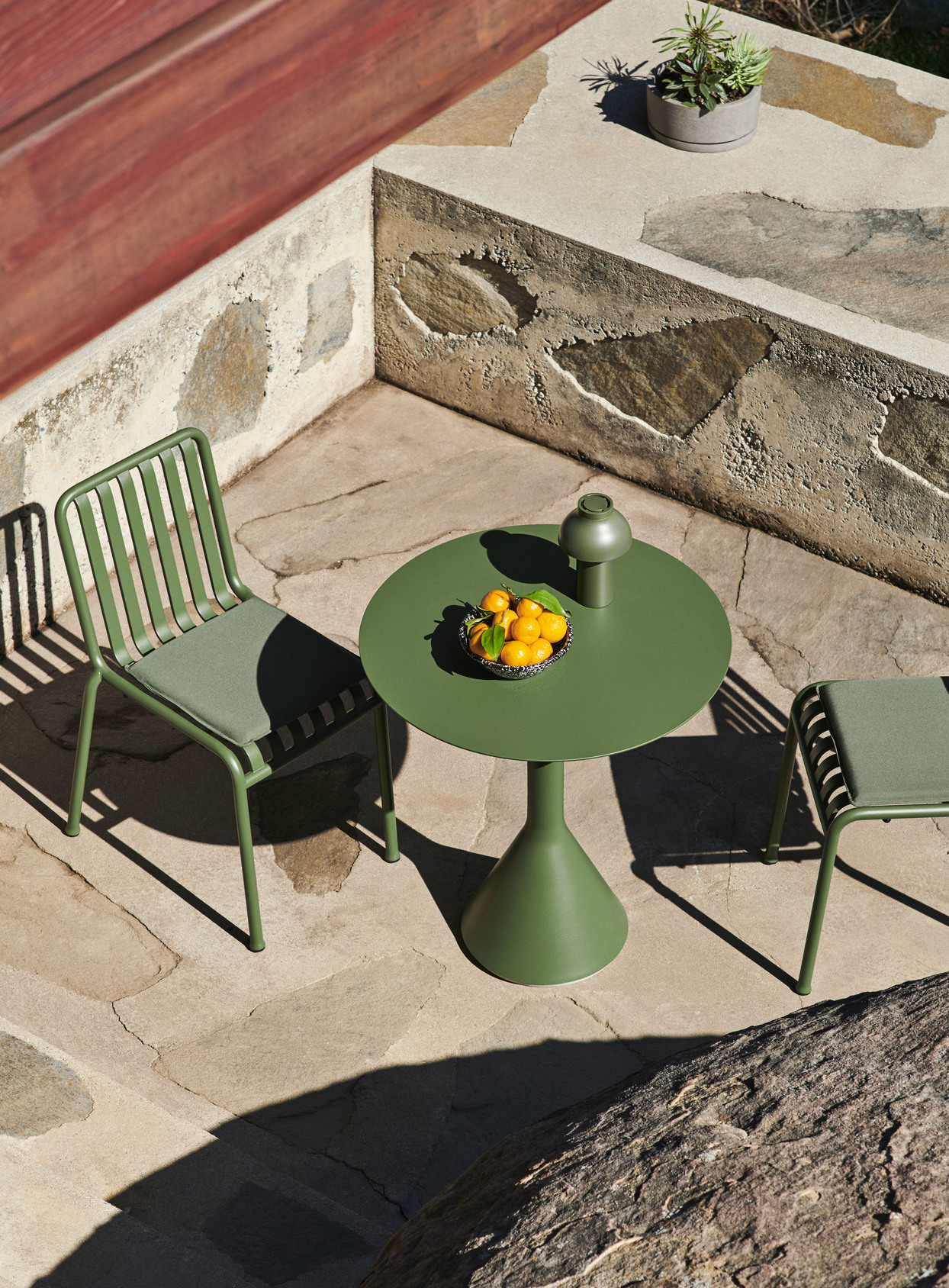 HAY Palissade dining chairs with seat cushions surround a round Palissade Cone table in green