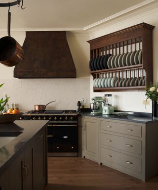 A vintage-looking plate rack is a statement piece in a dark, moody kitchen