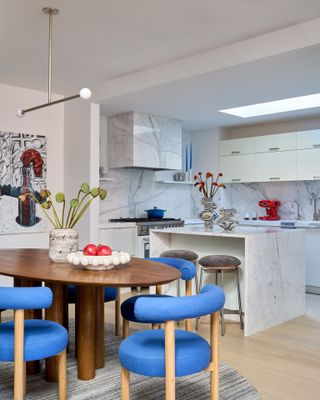 kitchen with white walls, wood dining table and seats in vibrant blue velvet