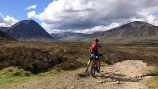 Female rider on the West Highland Way taking in the views of the entrance to Glencoe