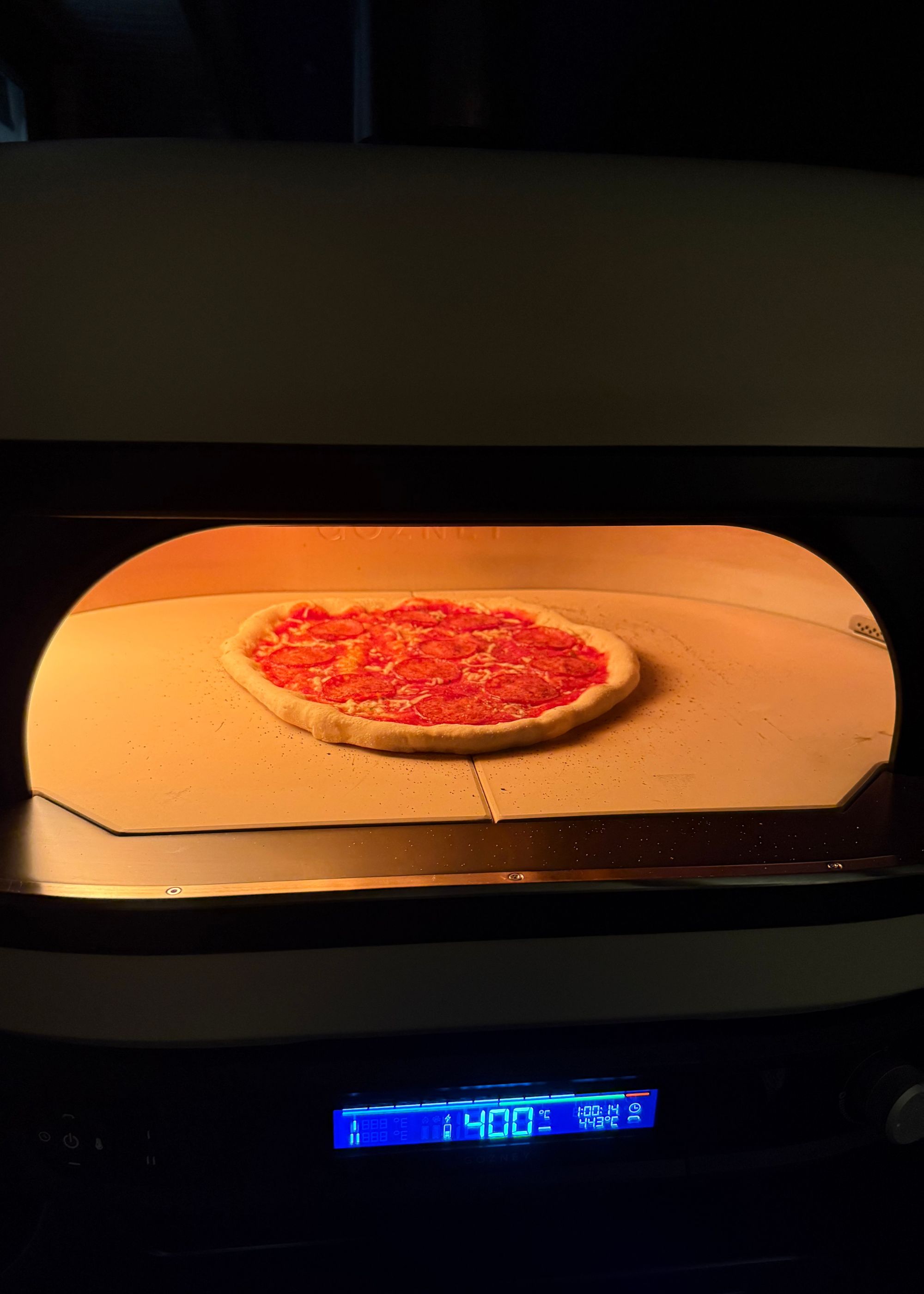 A close up of a pizza cooking inside Gozney's Dome XL Gen 2 with the built-in thermometer reading 400 degrees