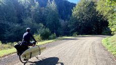 Isobel's partner riding with surfboard attached 