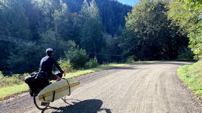 Isobel&#039;s partner riding with surfboard attached 