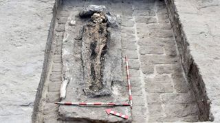 a photo of an excavated tomb with a skeleton in the middle