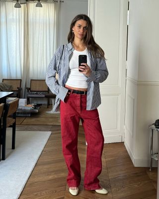 Woman wearing a summer travel outfit of red jeans and a striped shirt.