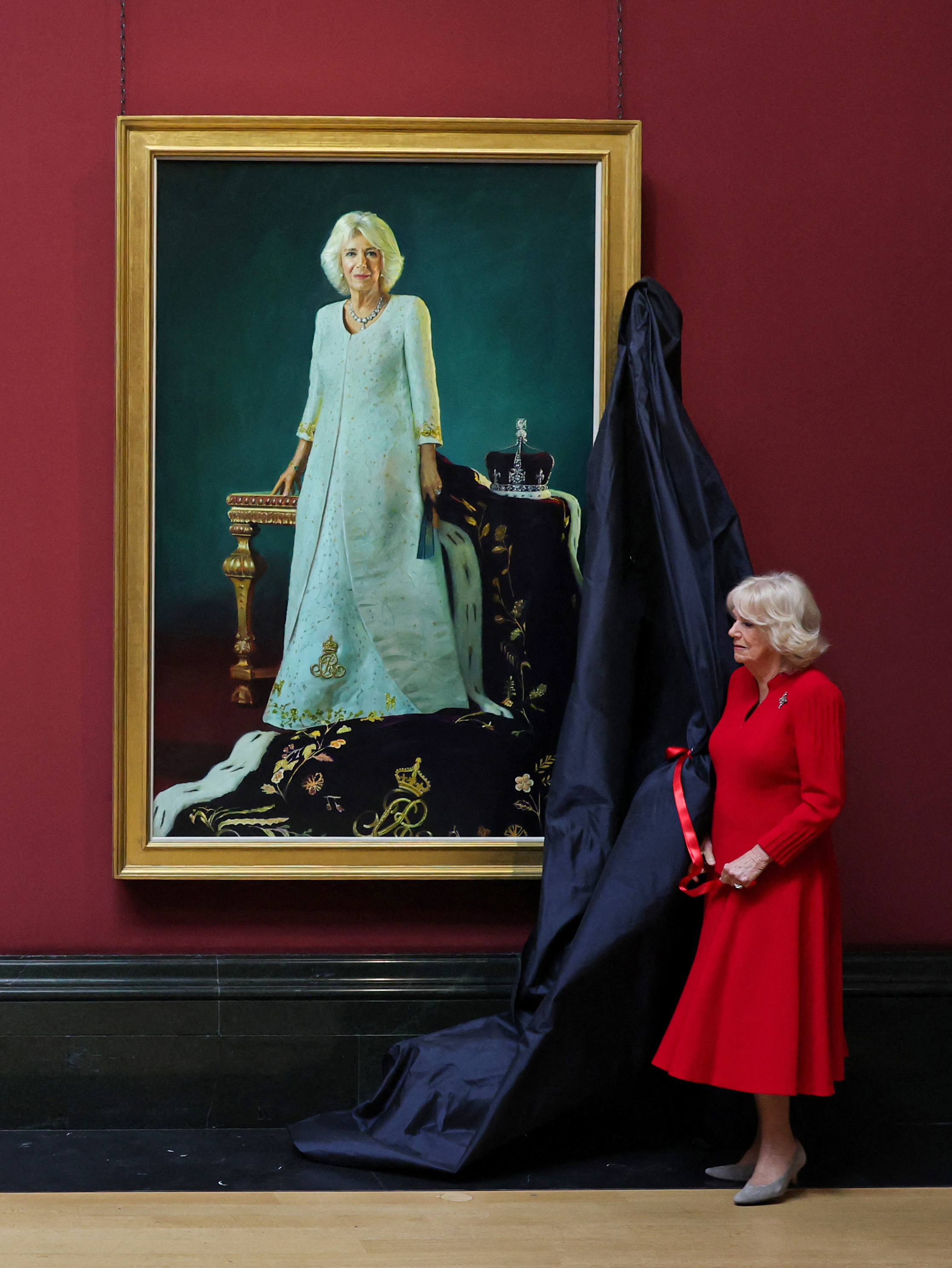 Queen Camilla unveiling her coronation portrait in a red dress
