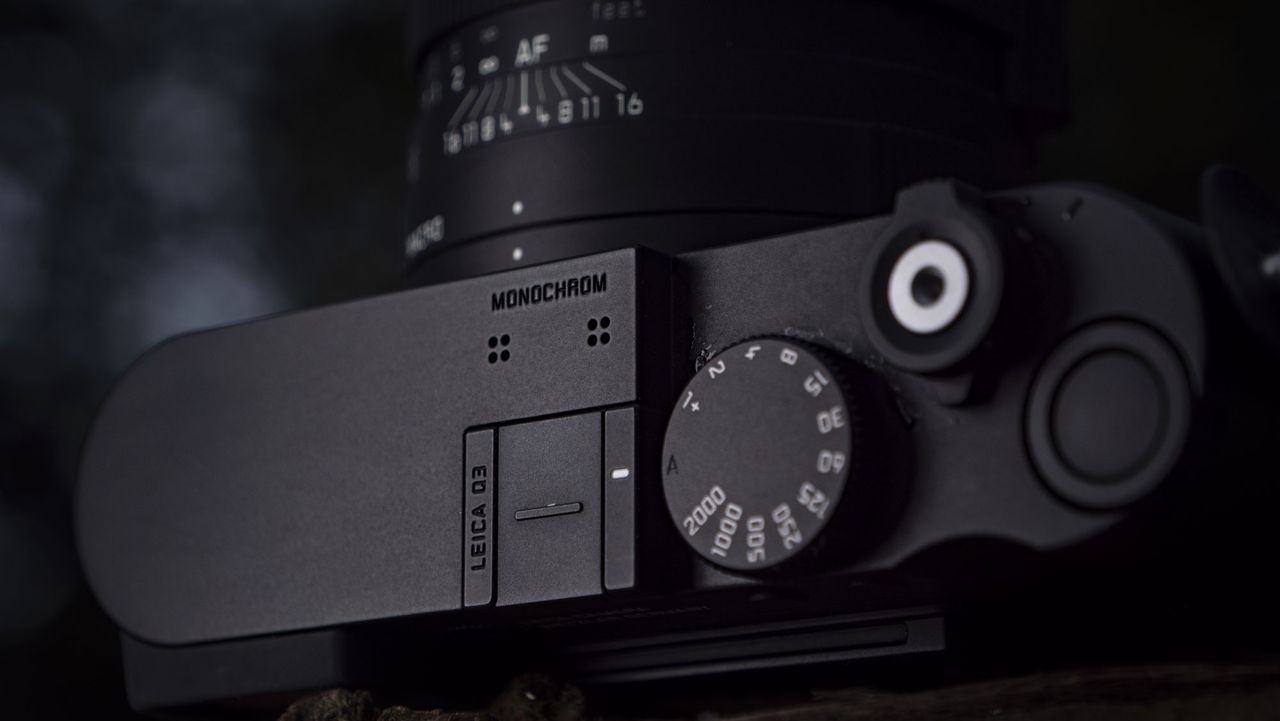 Leica Q3 Monochrom compact camera outside on a snow-dusted log