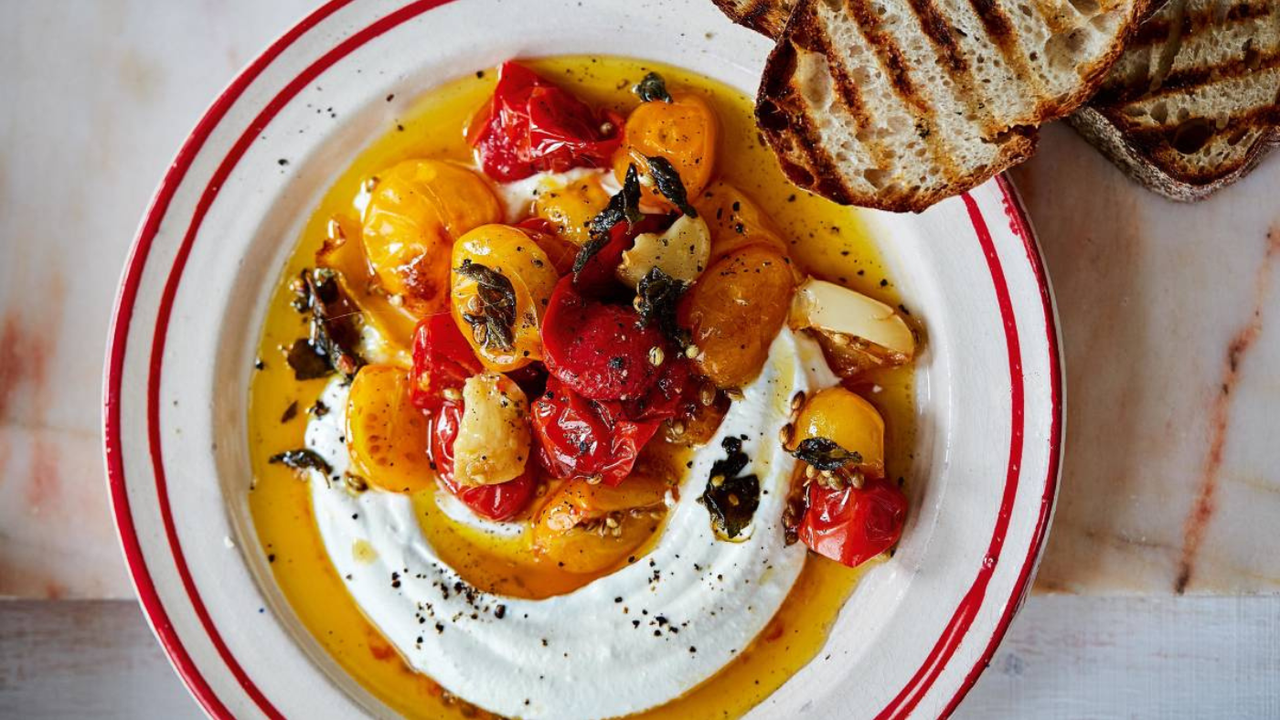 A plate of whipped feta topped with tomatoes and a side of bread