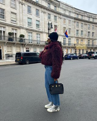 woman in maroon fur jacket and jeans