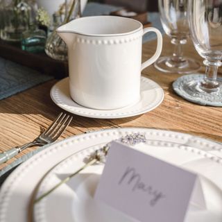 a small sauce jug with saucer, table setting and place name tag with the name Mary