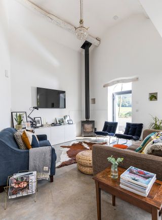 A white minimalist modern living room idea with blue chairs and stove in corner