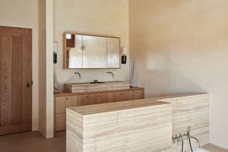 A bathroom with mixed materials including travertine and wood