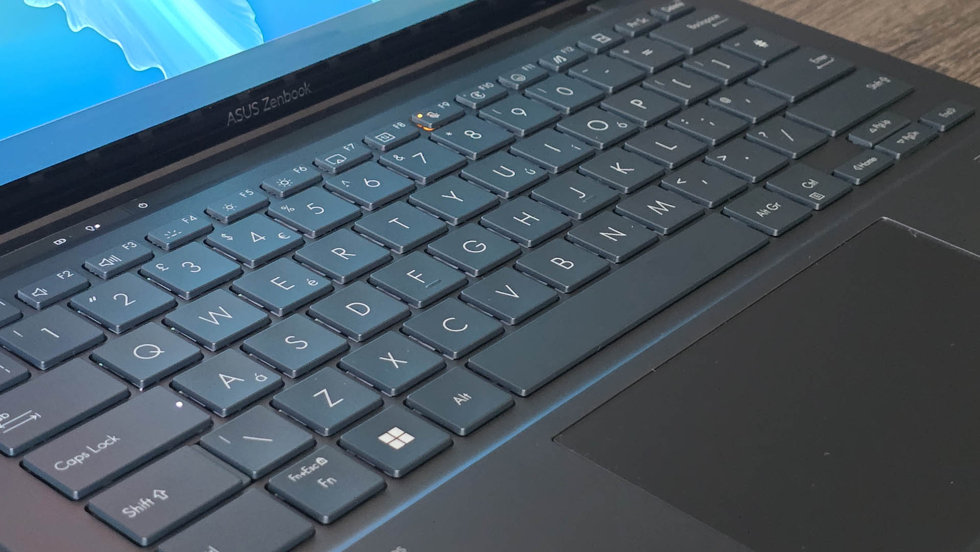 The Asus Zenbook Duo laptop photographed on a wooden desk.