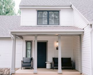 home exterior with white walls, gray door and window frames and two gray chairs on porch