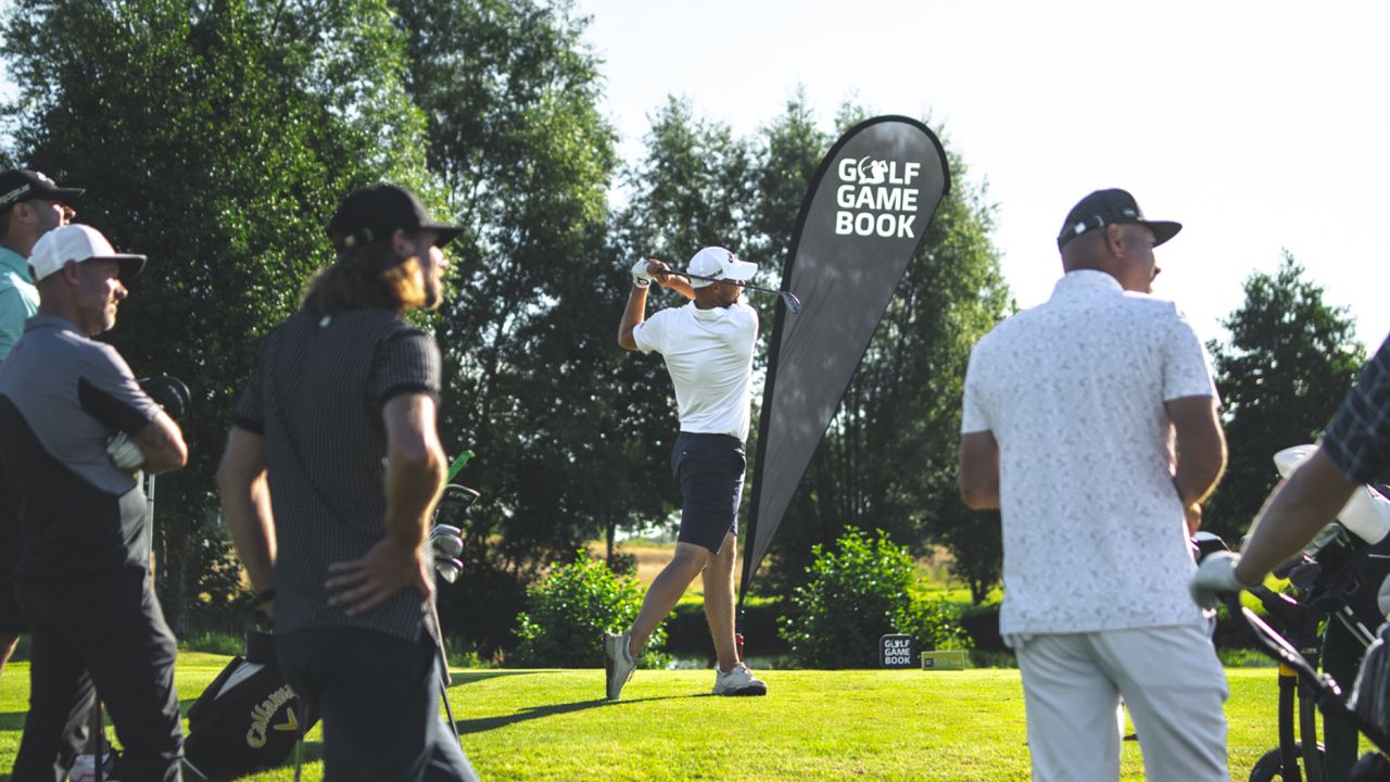 Golfer tees off surrounded by watching golfers