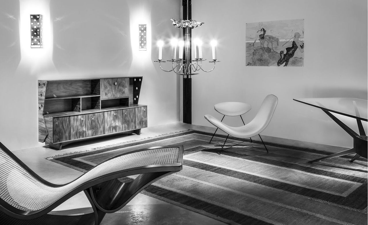 Design &#039;warehouse&#039; showing a contemporary lounge chaise, bar cabinet, and a U-shaped armchair. The photo is black &amp; white.