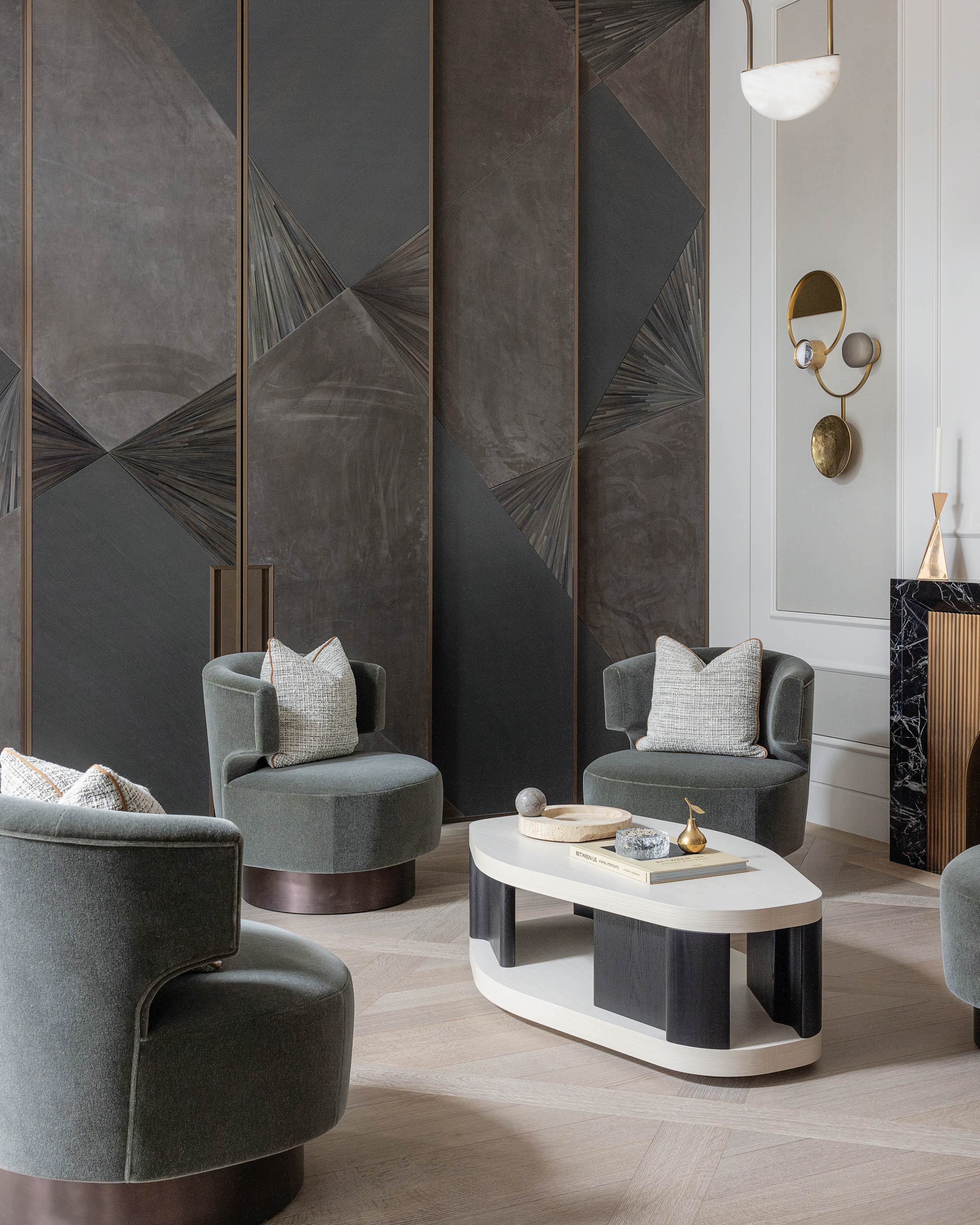 Basement lounge with grey polished plaster panels, teal chairs and black and white coffee table