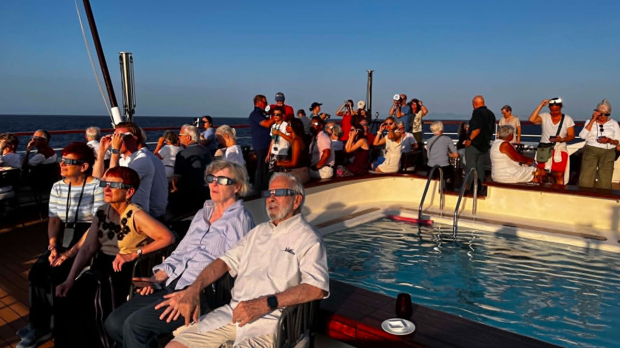 A weather satellite 22,000 miles above Earth saved my 2026 total solar eclipse cruise on the Mediterranean Sea 3 MyCelestialApp people sit on the deck of a ship wearing paper sunglasses, looking skyward