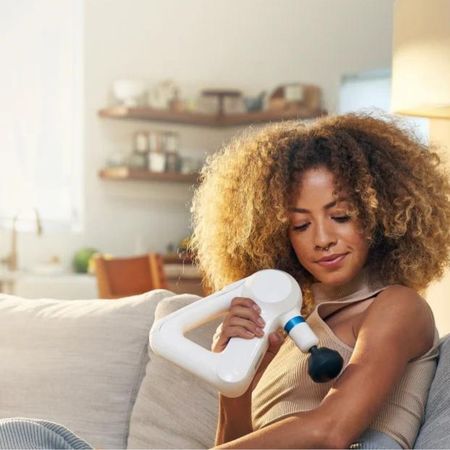 A woman having brought a massage gun Cyber Monday deals