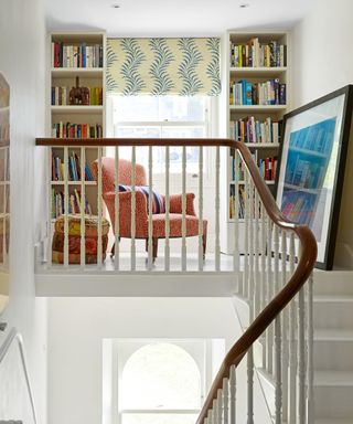 mezzanine and staircase with bookcases and orange armchair and blue and white blind