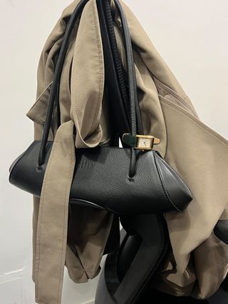 A photo of a shoulder bag on the back of an office chair with a Heaven Mayhem watch wrapped on one strap.