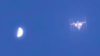 a T-shaped space station beside a half-orb on a blue sky