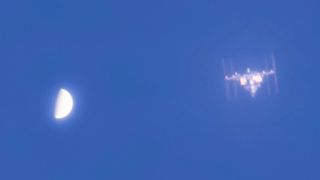 a T-shaped space station beside a half-orb on a blue sky
