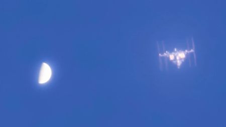 a T-shaped space station beside a half-orb on a blue sky