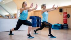Two women exercising with core sliders under their feet in a fitness studio