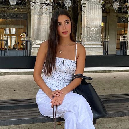 Tamara Mory wearing a white-and-blue floral linen camisole with white linen trousers in Paris.