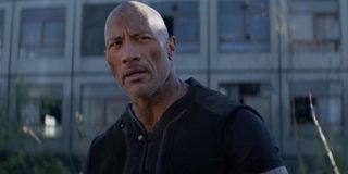 Hobbs and Shaw Dwayne Johnson standing in front of an abandoned building, smouldering