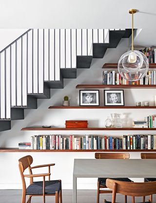 White room with open shelves below stairs