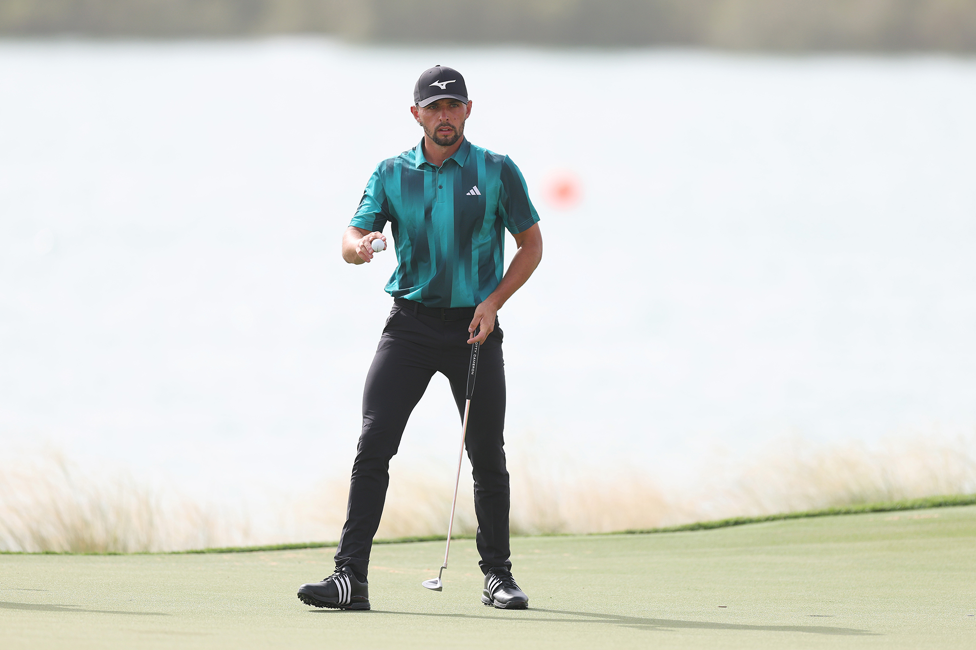 Marco Penge holding the golf ball up to the crowd in appreciation after holing a putt on the green in Abu Dhabi