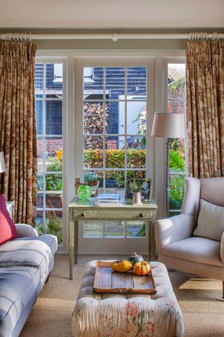 patio doors with floral curtains flanked by two cosy armchairs