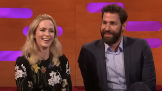 Emily Blunt and John Krasinski sit smiling next to each other on The Graham Norton Show. 